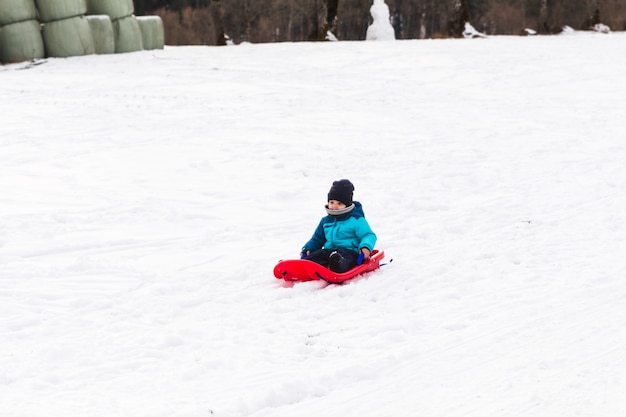 Ragazzino con la slitta rossa nella neve