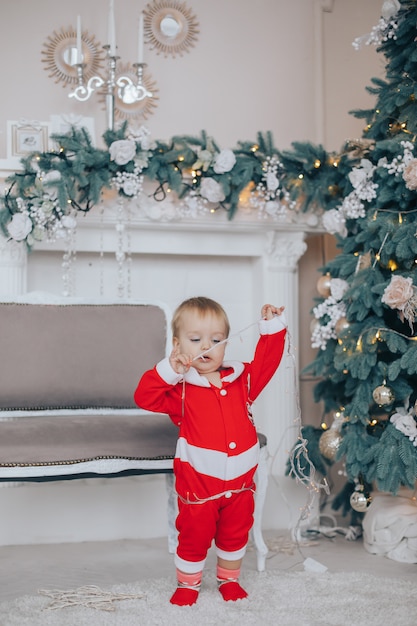 Little boy with Santa costume near the Christmas tree