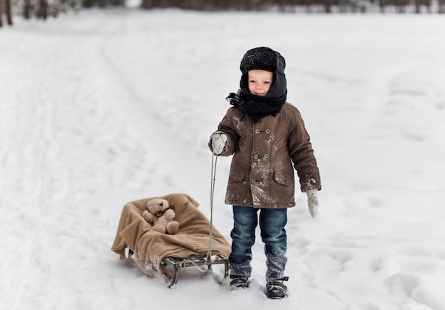 Little boy with sled in winter forest