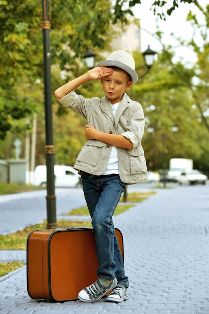 Photo little boy with suitcase in the park