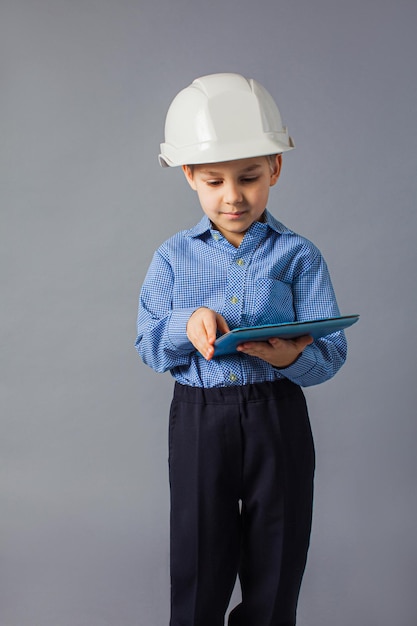 the little boy with tablet dressed in a costume of engineer