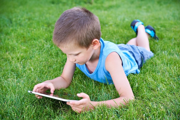 Little boy with tablet pc on grass