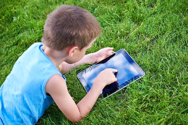 芝生の上のタブレット pc を持つ少年