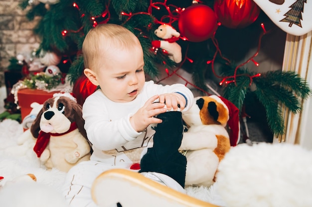 Little boy with toy near Christmas decor and Christmas tree