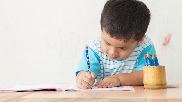 写真 小さな男の子は白い壁に紙を書いて、