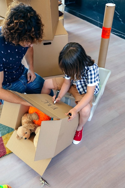 Little boy writing his name in a moving box with his father