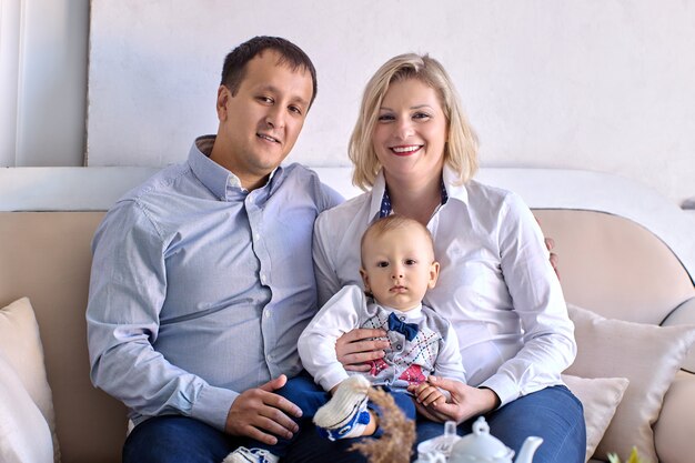 Little boy  years old with happy parents sit on sofa indoors