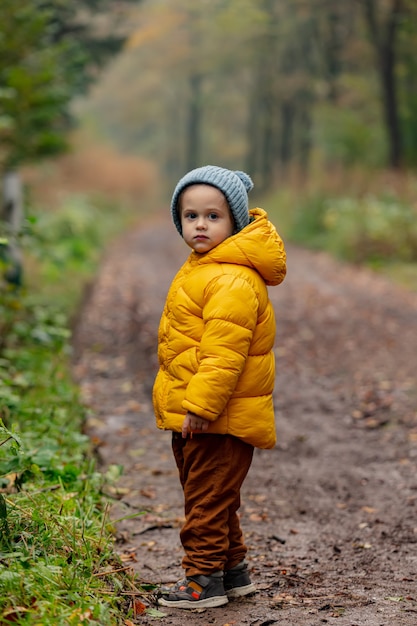 Little boy in yellow jacket stay in forest alone