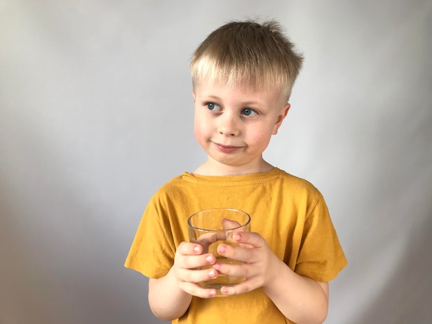 little boy in a yellow Tshirt drinks water