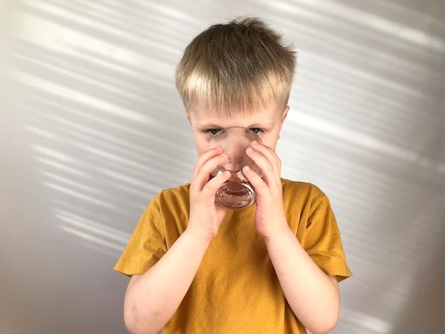 little boy in a yellow Tshirt drinks water