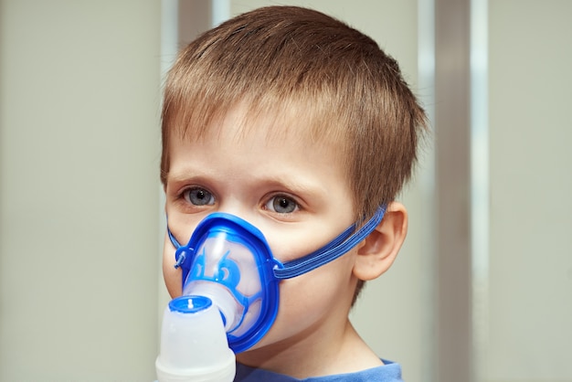 Little boyl using an inhaler indoors