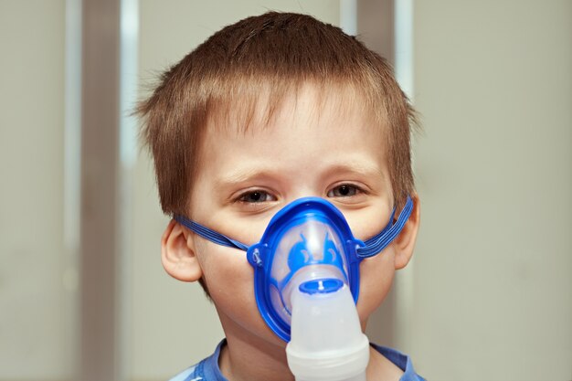 Little boyl using an inhaler indoors