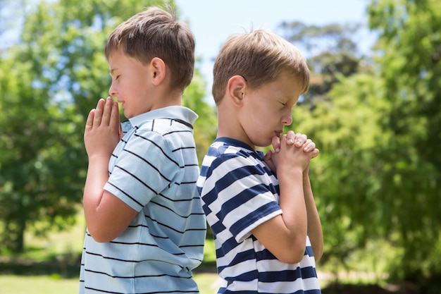 Photo little boys praying in the park