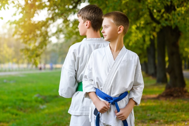 Little boys in white kimono during training karate exercises at summer outdoors