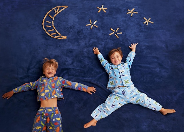 Photo little boys with big dreams two young boys lying underneath an imaginary moon and stars