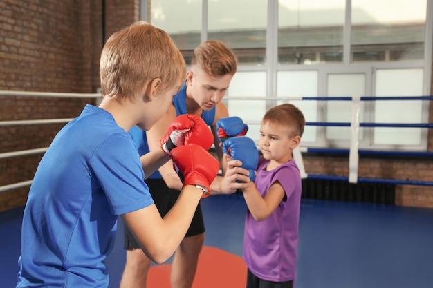 Little boys with trainer on boxing ring