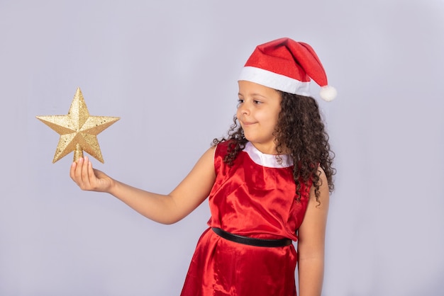 little Brazilian girl dressed with christmas costume holding golden star