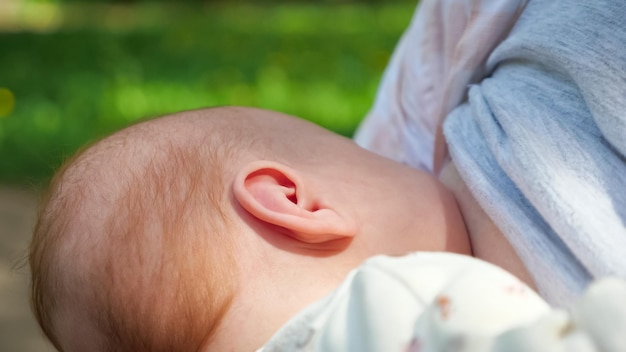 Little breastfed baby has easy breakfast in green park