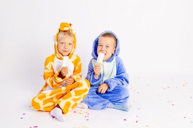 Little brothers in funny costumes sitting on a white background