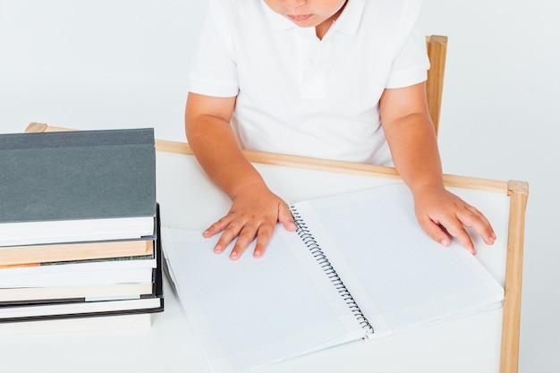 Little brunette girl at school smiling, sitting on a chair with books