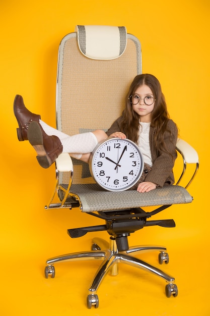 Little brunette girl with clocks in chair