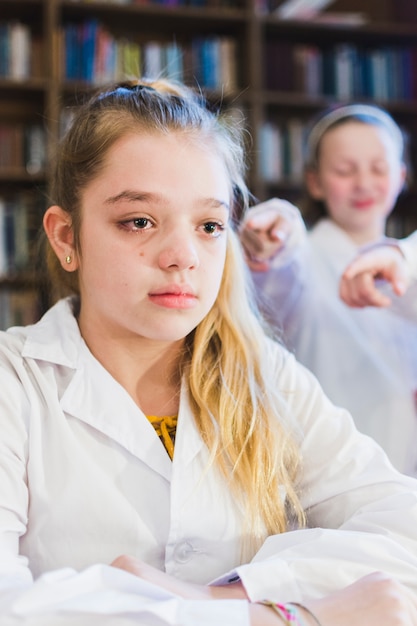 Little bullied girl crying in library 