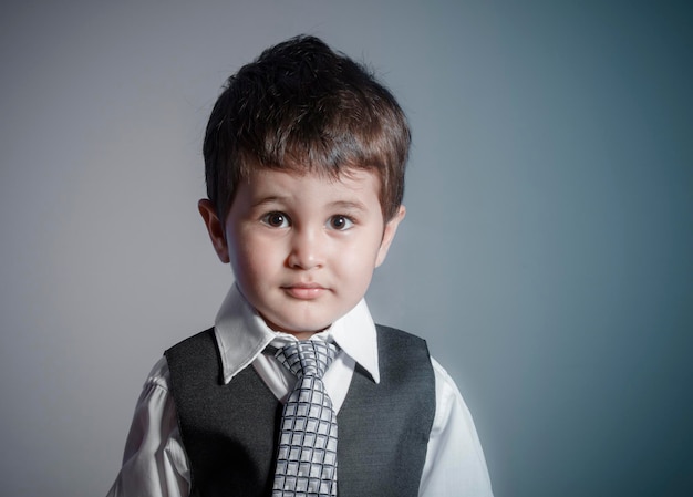 小さなビジネスマン、スーツに身を包んだ茶色の髪の少年、顔と面白い表情でネクタイ