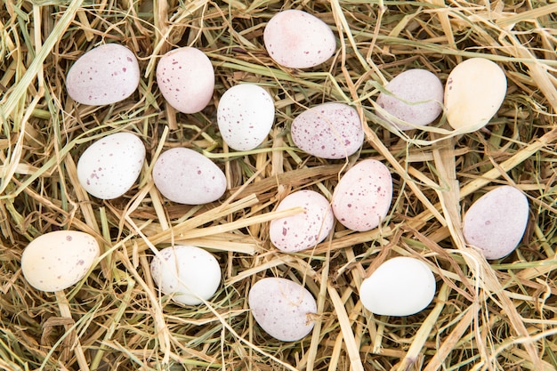 Foto piccole caramelle uova di pasqua sulla paglia