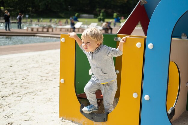 Photo little caucasian blond boy playing on kids playground in a sunny autumn day