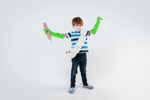 Little caucasian boy as a warrior in fight with coronavirus pandemic, with a face mask, sanitizer, thermometer and toilet paper bandoleer. Teenboy in war for human lives. Concept of childhood, health.