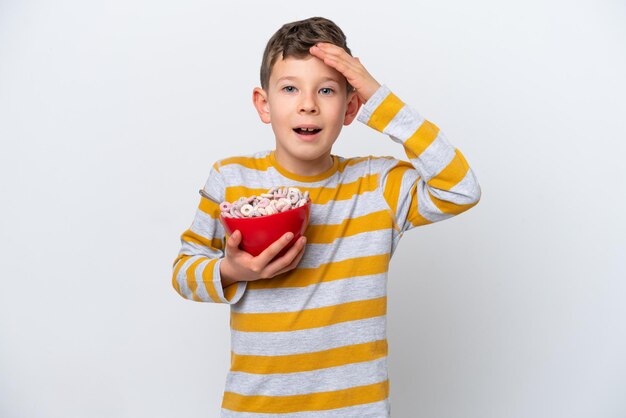 Little caucasian boy holding a cereal bowl isolated on white background with surprise expression