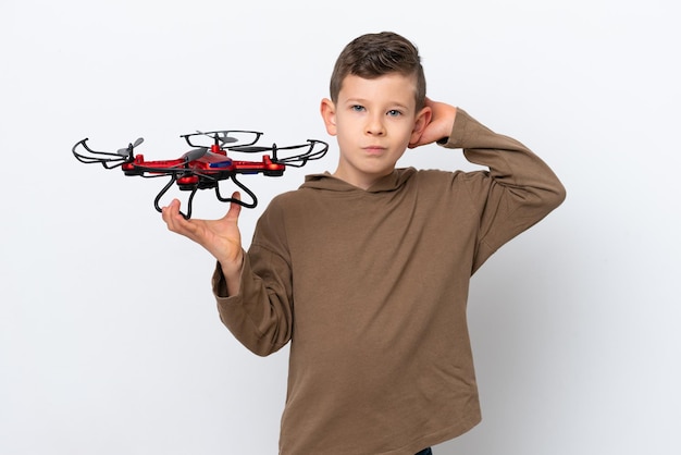 Little Caucasian boy holding a drone isolated on white background having doubts