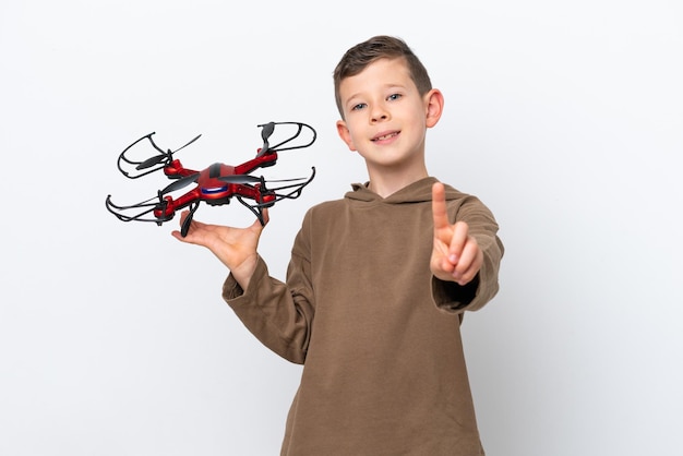 Little Caucasian boy holding a drone isolated on white background showing and lifting a finger