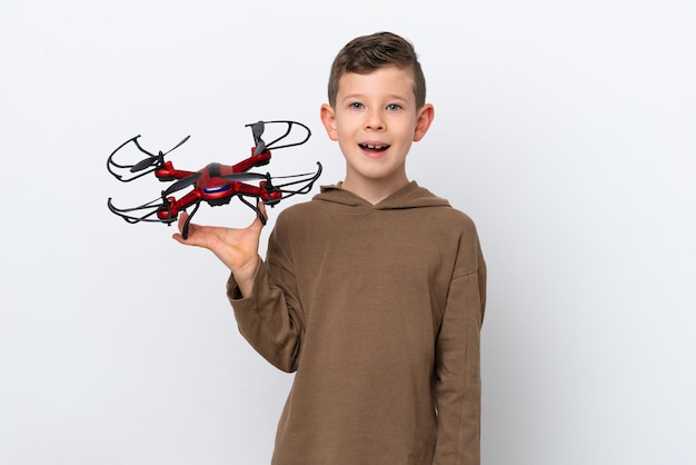 Little Caucasian boy holding a drone isolated on white background with surprise facial expression