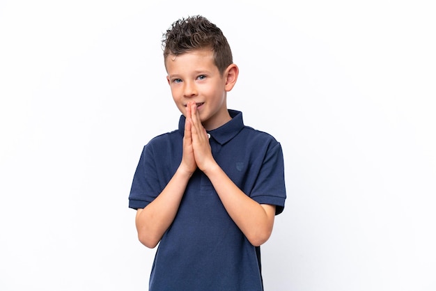 Photo little caucasian boy isolated on white background keeps palm together person asks for something