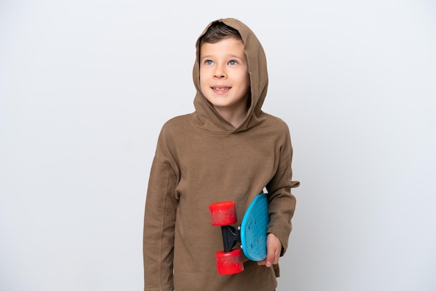 Little caucasian boy isolated on white background with a skate