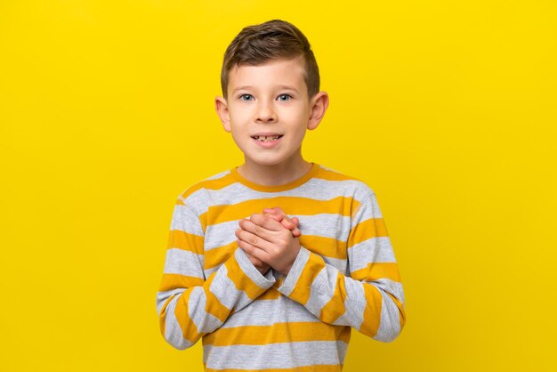 Little caucasian boy isolated on yellow background laughing