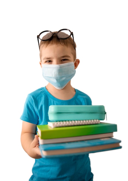 Little caucasian boy with medical face mask and books isolated on white background. Education, school during Covid-19. Isolation, distance and safety, coronavirus.