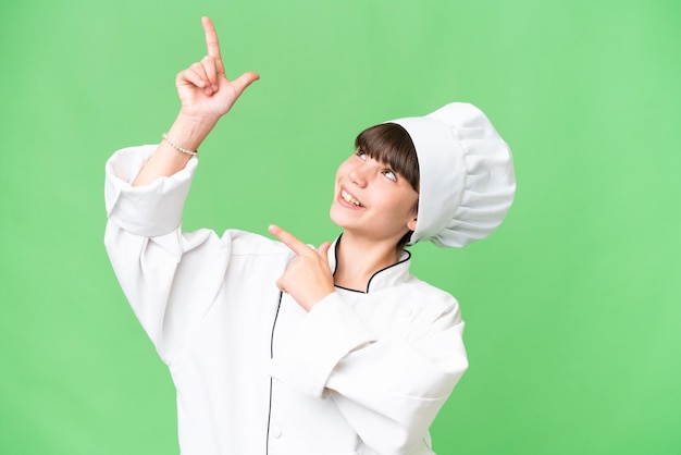 Little caucasian chef girl over isolated background pointing with the index finger a great idea