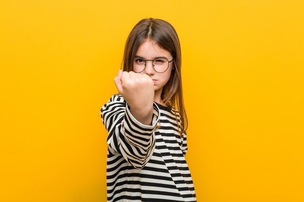 Little caucasian cute girl showing fist, aggressive facial expression.