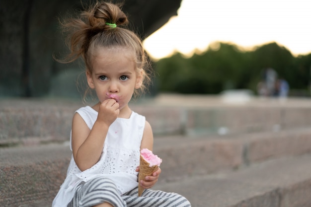 Little caucasian girl 3 years old eats ice cream closeup