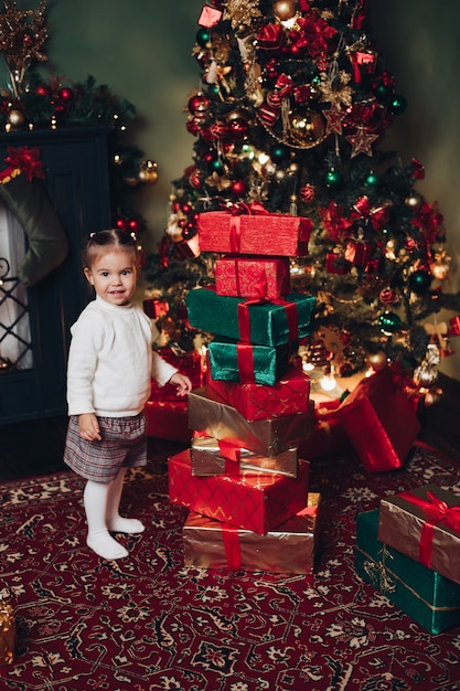 Little Caucasian girl and Christmas presents. Christmas tree.