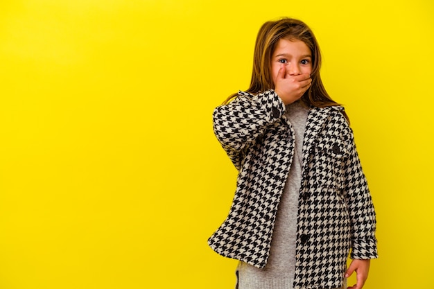 Little caucasian girl covering mouth with hand.