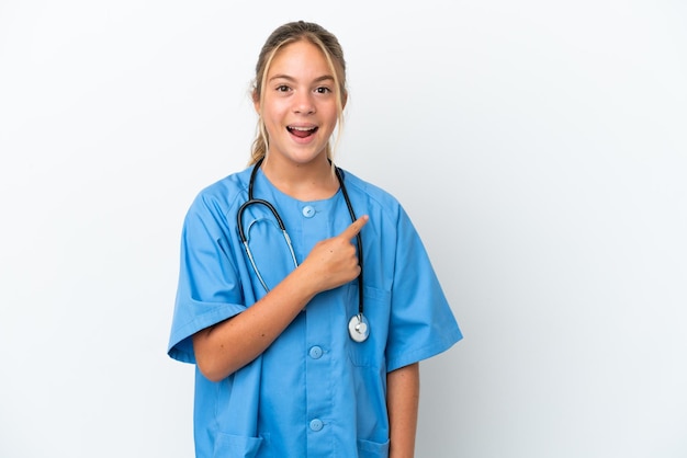 Little caucasian girl disguised as surgeon isolated on white background surprised and pointing side