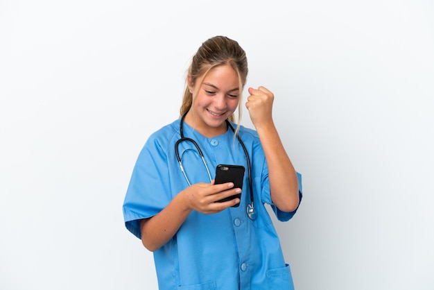 Photo little caucasian girl disguised as surgeon isolated on white background with phone in victory position