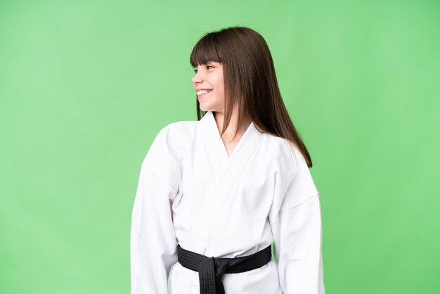 Little Caucasian girl doing karate over isolated background looking side