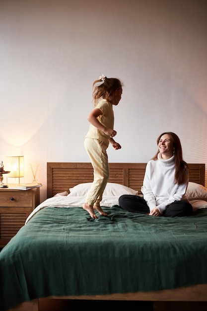 Little caucasian girl have fun with mother Jumping on bed christmas morning Happy family christmas concept