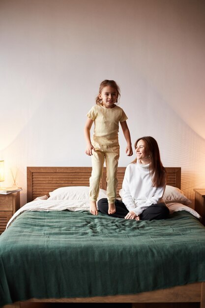 Little caucasian girl have fun with mother Jumping on bed christmas morning Happy family christmas concept