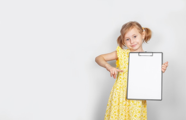 Little Caucasian girl holding a clipboard with a blank paper