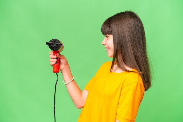 Little Caucasian girl holding a hairdryer over isolated background with happy expression